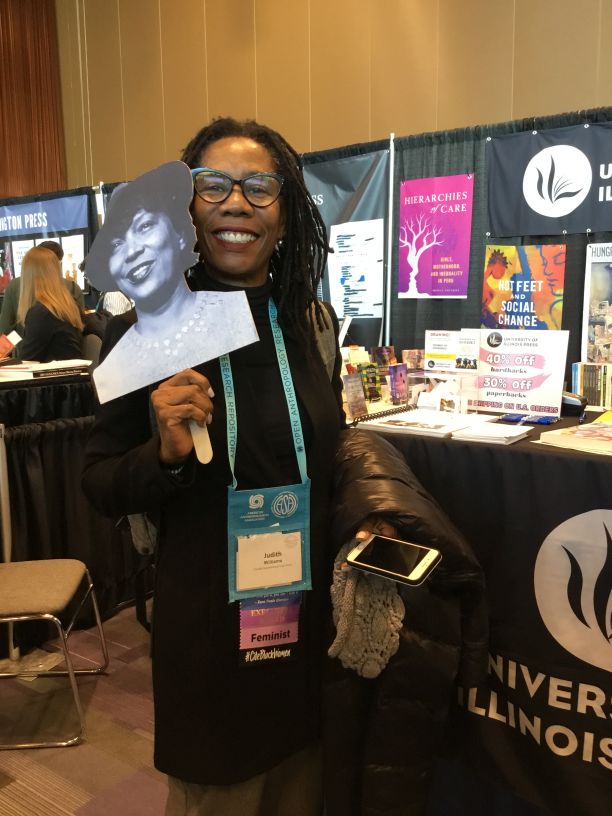 A woman holding a cardboard cutout of Zora Neale Hurston at the 2019 AAA/CASCA Annual Meeting.